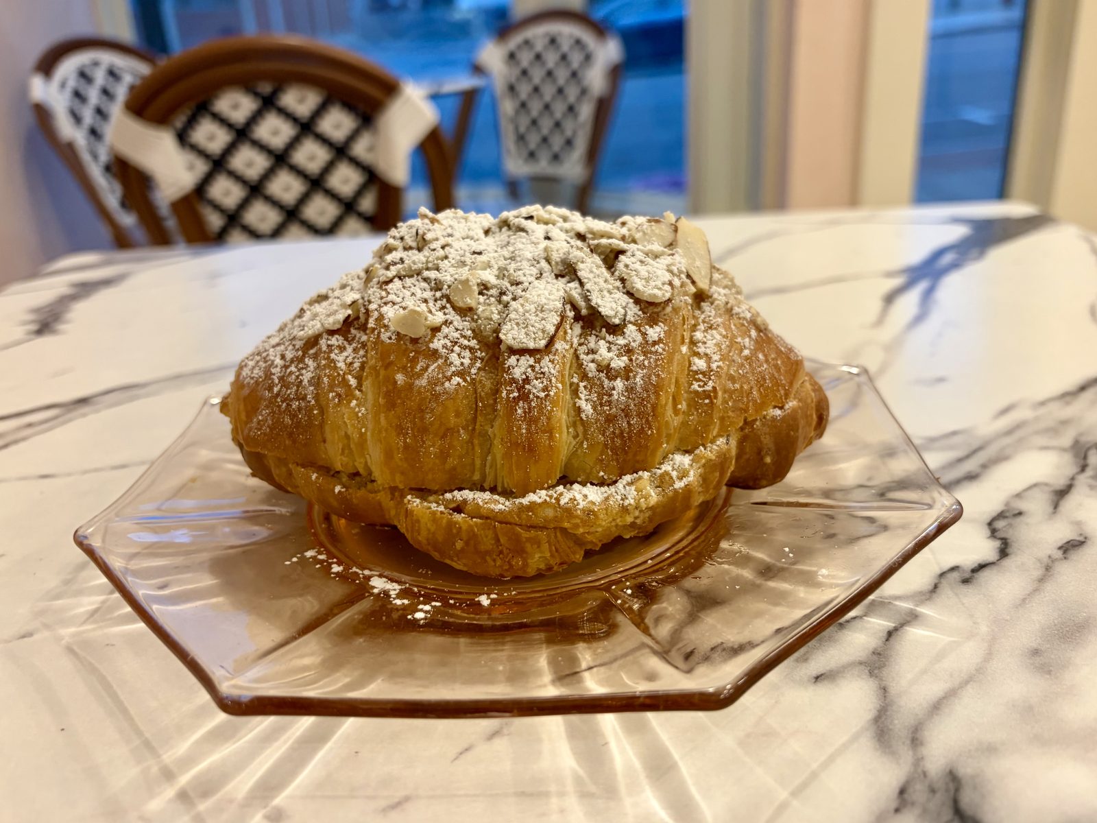 Almond croissant on a pink glass plate